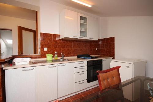 格拉达茨Apartment Gradac 6819a的厨房配有白色橱柜、水槽和炉灶。