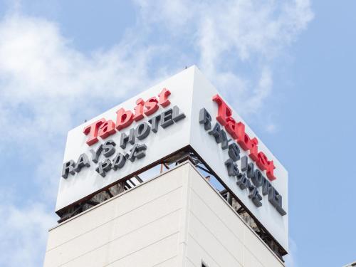 宫崎Tabist Rays Hotel Yakata的建筑物顶部的标志