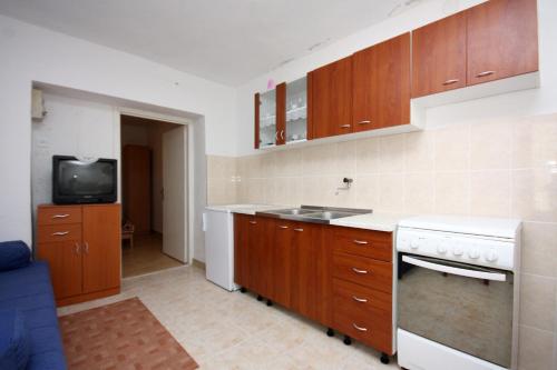 巴比诺波尔杰Apartments with a parking space Sobra, Mljet - 4926的一间带木制橱柜和水槽的厨房以及一台电视。