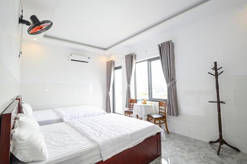 Hoi NghiaRuby Hotel - Tân Uyên - Bình Dương的白色卧室配有床和桌子