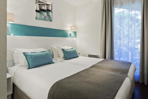 马赛馨乐庭马赛卡斯特拉娜酒店的卧室配有带蓝色枕头的大型白色床