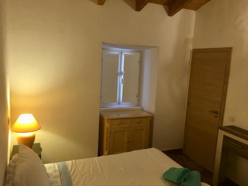 阿尔坎塔里利亚Casa do Pátio em Alcantarilha - Algarve的一间卧室设有床、窗户和一盏灯。