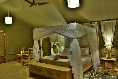 塔勒克Mara Maisha Camp的一间帐篷内带天蓬床的卧室