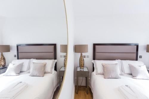 伦敦The Dorset Suite - Stylish New 1 Bedroom Apartment In Marylebone的一间卧室配有两张白色的床和镜子