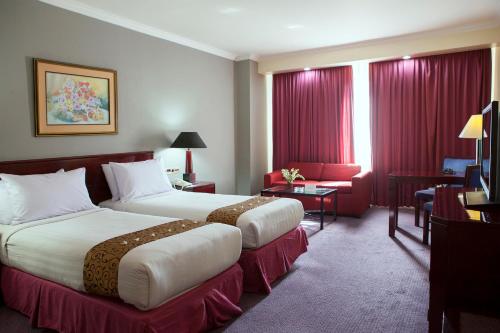 泗水Surabaya Suites Hotel Powered by Archipelago的配有红色窗帘的酒店客房的两张床