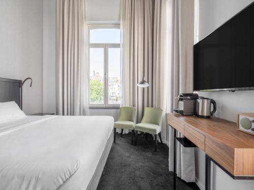 布鲁塞尔numa l Lief的酒店客房配有一张床和一张书桌及一台电视