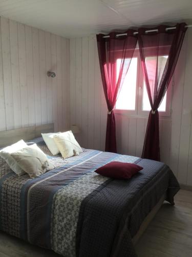 Saint-Sylvestre-sur-LotDouceur d été的一间卧室配有一张带红色窗帘的床和一扇窗户