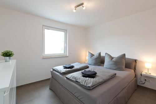 勒伯尔Apartment unter den Kiefern 93的白色卧室配有带两个枕头的床