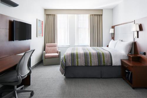 休斯顿Club Quarters Hotel Downton, Houston的酒店客房配有一张床、一张桌子和一把椅子。