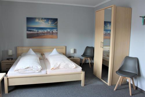 克洛彭堡Hotel Schlömer的一间卧室配有一张带两把椅子和镜子的床