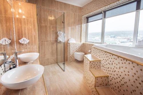 托尔斯港哈夫尼亚酒店的浴室配有2个盥洗盆、淋浴和浴缸。