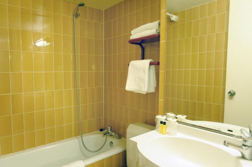 巴黎New Hotel Saint Lazare的浴室配有盥洗盆、卫生间和浴缸。