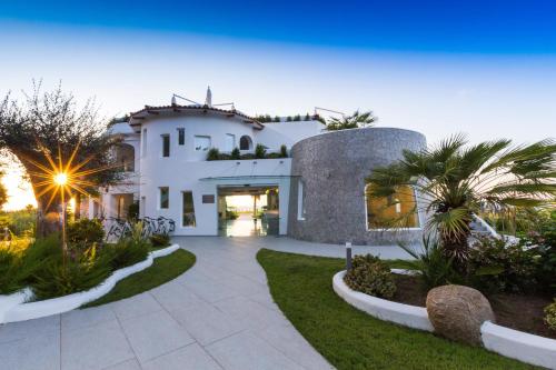 帕尔盖利亚Infinity Resort Tropea的一座白色的大房子,设有种有棕榈树的庭院