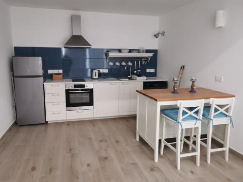 利马索尔Nostalgia apts的厨房配有白色橱柜和木桌及椅子