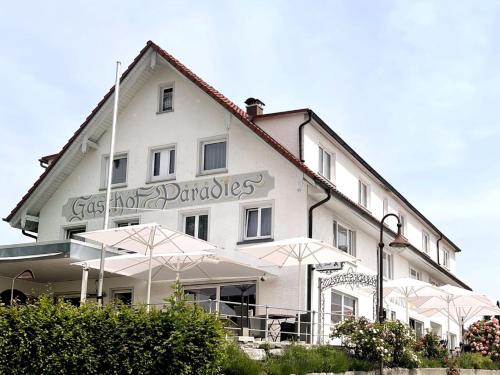 VogtAdam & Eva Gasthof Paradies mit Hotel的前面有雨伞的白色建筑