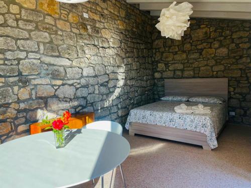 CammarataLA CASETTA SULLE NUVOLE PETRA的一间卧室配有一张床、一张桌子和石墙