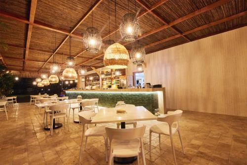 普拉亚斯Karibao Resort Town的餐厅设有白色的桌椅和吊灯。