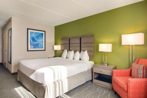 新费城荷兰山谷贝斯特韦斯特酒店的一间卧室配有一张大床和一张红色椅子