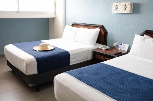 梅里达Hotel Los Aluxes的酒店客房,设有两张床,顶部有顶帽子