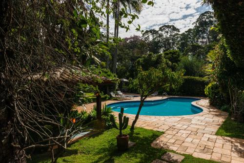 布拉干萨-保利斯塔Pousada Recanto das Rosas的一座树木繁茂的庭院内的游泳池
