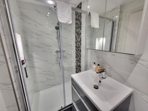 芬奇利Garland Modern 4 Bedroom Central Apartment London的白色的浴室设有水槽和淋浴。