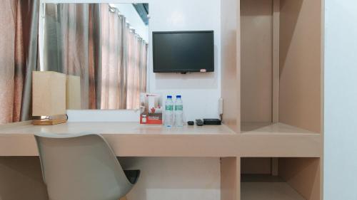 伊洛伊洛RedDoorz Near Iloilo International Airport的客房设有一张桌子、一台电视和一把椅子