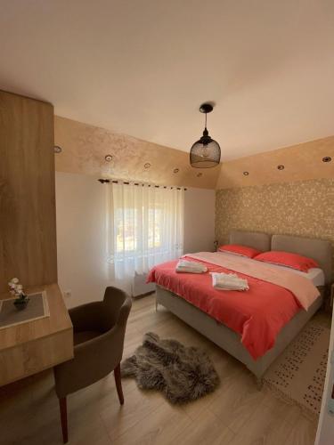 新瓦罗什Apartman Zara Zlatar的一间卧室配有红色的床、一张桌子和一把椅子