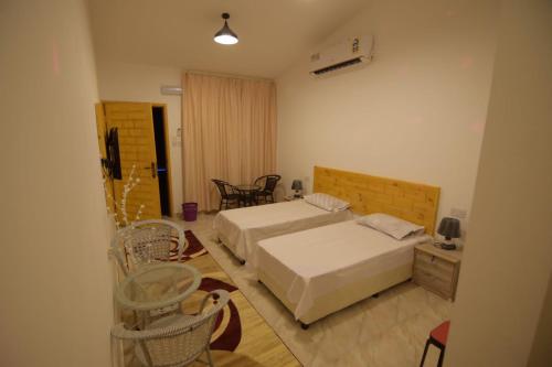 阿尔哈德السكون لبيوت الضيافة و شاليه AL Sukun For Guest Houses & Chalet的一间卧室配有两张床和一张桌子及椅子