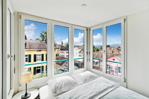 苏黎世Spacious Central Apartments HOTING的卧室设有大窗户和一张带白色床单的床