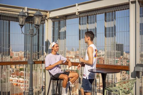 巴塞罗那呃班尼巴塞罗那旅馆的两个人坐在一个眺望着城市的阳台