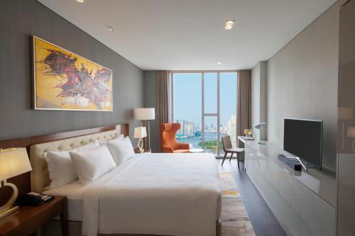 胡志明市Sedona Suites Ho Chi Minh City的酒店客房,配有床和电视