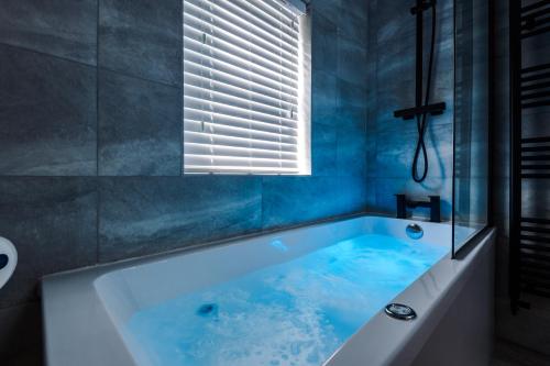 切斯特Faulkner House的蓝色的浴室设有浴缸和窗户