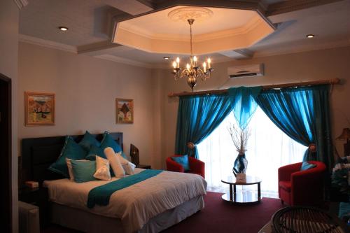 Mohales HoekHotel Mount Maluti - Lesotho的一间卧室配有一张带蓝色窗帘的床和一扇窗户