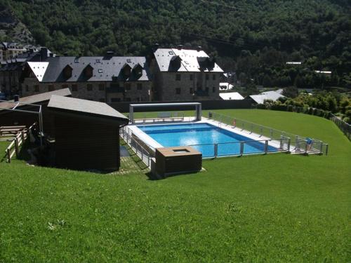 伊斯卡日拉Alojamiento Escarrilla Pirineos的绿草丛中的一个大型游泳池
