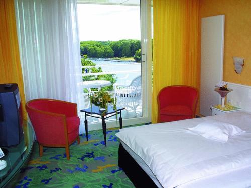 巴特塞格贝格维达利亚海滨酒店的一间卧室配有一张床、两把椅子和一个窗户