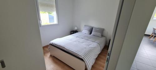 La ChevrolièreLA THOMASERIE的白色卧室配有带枕头的床和窗户