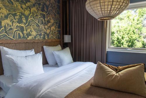 哥德堡阿尔肯及艺术花园Spa酒店的卧室配有带白色枕头的床和窗户。