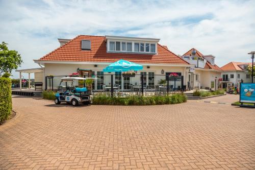 海滨诺德韦克EuroParcs Noordwijkse Duinen的前面有一把雨伞和高尔夫球车的房子