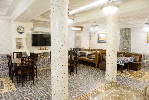 撒马尔罕Durdona Guest House的一间设有柱子的餐厅和一间设有桌子的用餐室