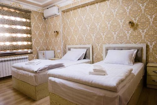 撒马尔罕Durdona Guest House的配有2张单人床的带墙壁客房