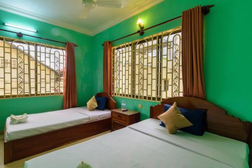 暹粒Happy Heng Heang Guesthouse的配有两张床铺的绿色墙壁和窗户