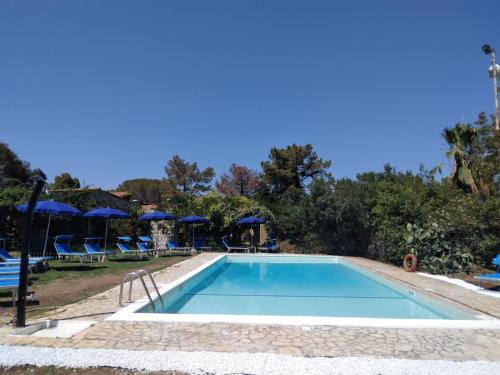 费拉约港阿雷葛罗塔利亚厄尔巴高尔夫酒店的度假村的游泳池,配有椅子和遮阳伞