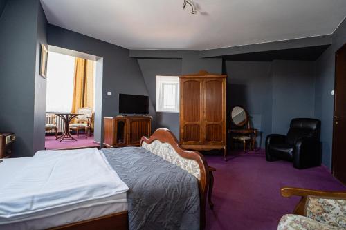 托伦波洛尼亚酒店的一间卧室配有一张床、一台电视和一把椅子