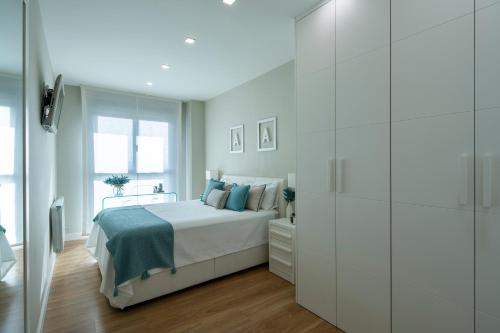 格拉纳达GUNI SUITES JARDINEs的一间白色的卧室,配有一张床和玻璃墙