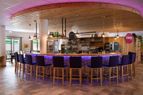 格绍达斯坦阿尔卑斯酷易酒店的餐厅内的酒吧配有蓝色椅子和柜台