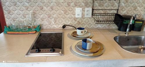 科鲁里皮Vila Bello Pontal的厨房柜台设有水槽和2个杯子及盘子