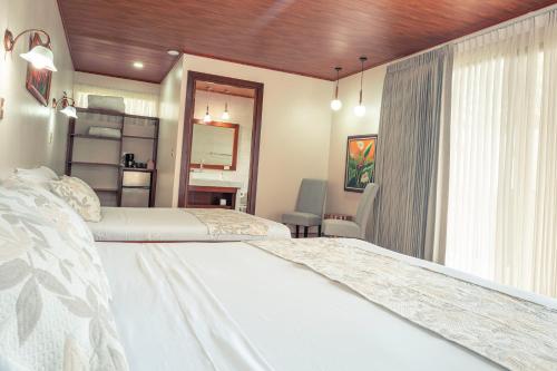 福尔图纳Miradas Arenal Hotel & Hotsprings的一间卧室设有两张床和窗户。