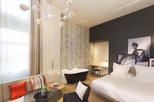巴黎三科考德旅馆的一间卧室配有一张床,浴室设有浴缸