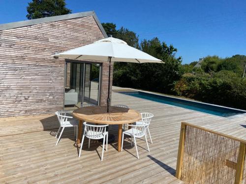 LandunvezMagnifique villa avec piscine, à 5 min des plages的甲板上配有一张木桌和椅子及遮阳伞