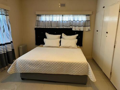 莫里维尔The Big Five Bed and breakfast的一间卧室配有一张带白色床单的床和一扇窗户。